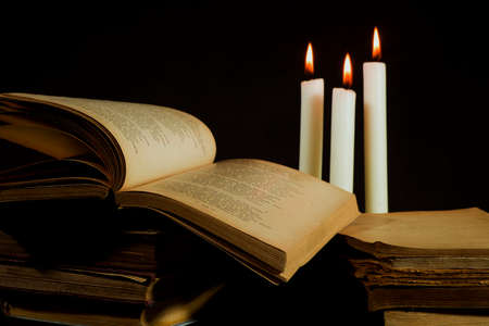 Knowledge concept, heaps of old destroyed books on a background of candlesの写真素材