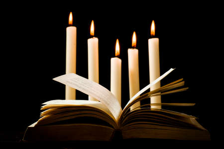 Knowledge concept, open book on the background of lighted candlesの写真素材