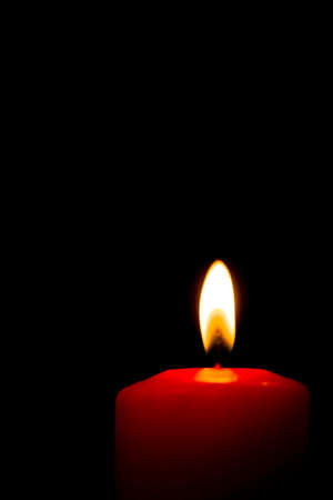 A red lit candle isolated on a black backgroundの写真素材