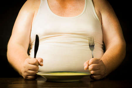Man with cutlery in hand sitting on a plateの写真素材