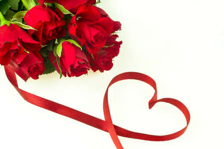 Romantic bouquet of red roses on a white background with a ribbon in the shape of a heart, looking from aboveの写真素材