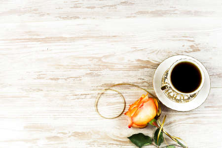 A cup of coffee, and an orange rose on a background of vintage boardsの写真素材