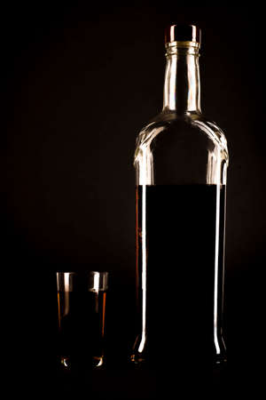 Silhouette of a bottle of alcohol with a glass on a black background isolatedの写真素材
