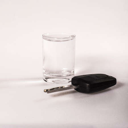 Concept of driving under the influence of alcohol - car keys, a glass of alcohol on a white backgroundの写真素材