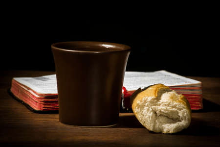 The concept of the multiplication of bread and wine in the Christian religion, bread and a brown cup of wine on the background of the book for prayerの写真素材