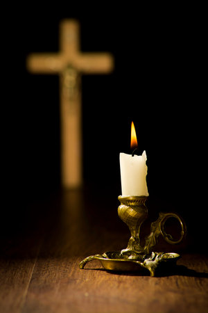 Christian religion concept, lit candle in a candlestick on a crucifix background