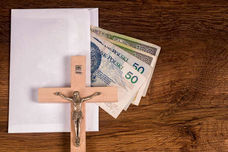 A crucifix lying on an envelope with Polish banknotes in the backgroundの写真素材