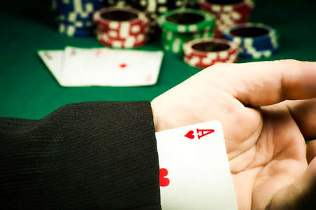 Gambling fraud concept. Card hidden in the sleeve on the background of chips and cardsの写真素材