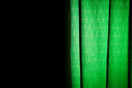 Half-exposed green curtain on a black backgroundの写真素材