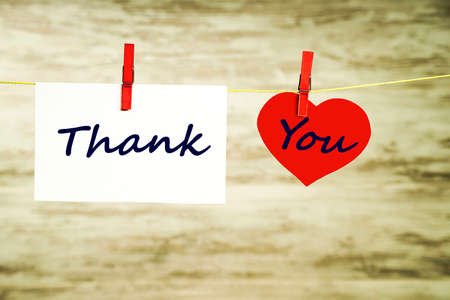 A card and a red heart hanging on a string, fastened with red clasps with the words thank youの写真素材