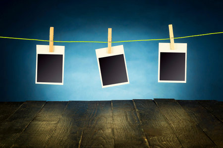 Photo frames are fastened with clips, hanging on boards and illuminated blue background