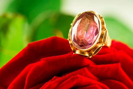 Gold ring with sapphire on a red rose backgroundの写真素材