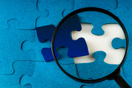 Magnifier on the background of Blue puzzle with one missing piece