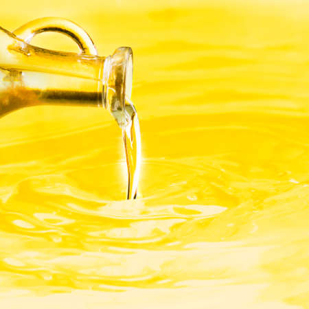 Poured oil from a bottle against a yellow oil backgroundの写真素材