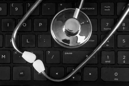 A stethoscope lying on a black computer keyboardの写真素材