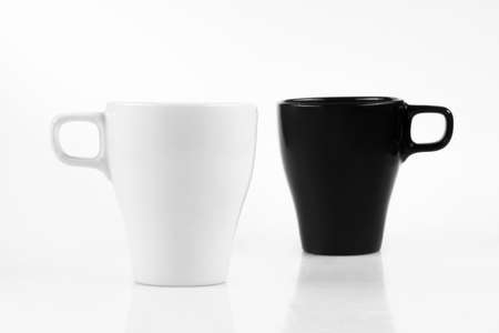 White cup and black mug isolated on a white backgroundの写真素材