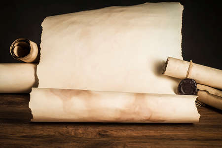 Scrolls of papyrus on the brown countertop of old boards on a dark backgroundの写真素材