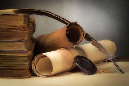 Papyrus scrolls on a light table top with books and a penの写真素材
