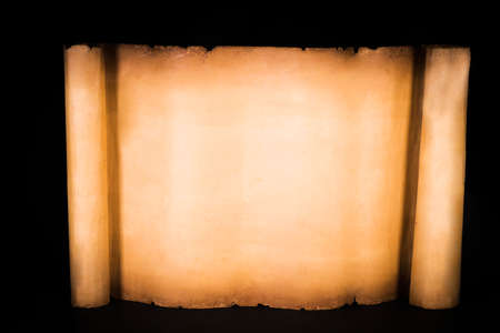 Unrolled scroll of parchment on a black backgroundの写真素材