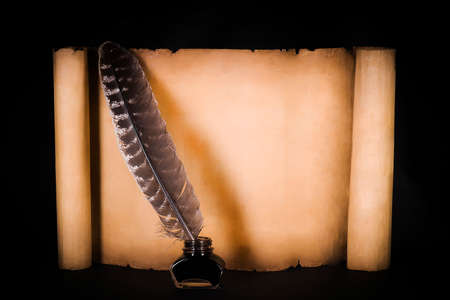 Unrolled scroll of parchment with a pen on a black backgroundの写真素材