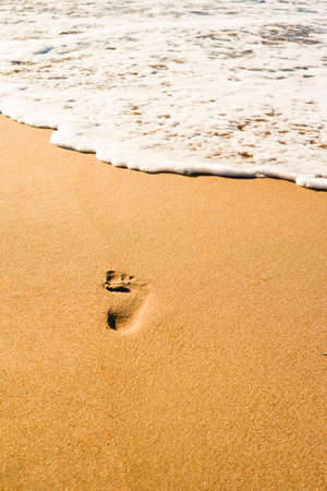 Footprints in the sand flooded with sea wavesの写真素材