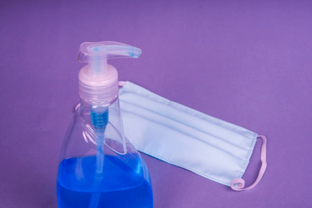 Virus protection concept - Sanitizing hand cleaner spray with cotton mask on blue backgroundの写真素材