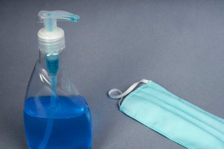 Virus protection concept - Sanitizing hand cleaner spray with cotton mask on blue backgroundの写真素材