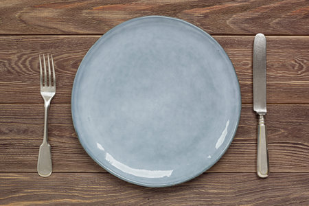 Ceramic plate and cutlery on a wooden worktop