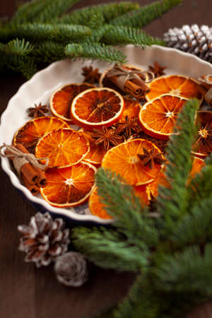 Christmas - natural Christmas decorations on a white plate - dried oranges, and cinnamonの写真素材
