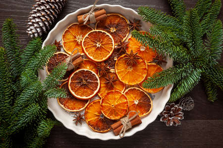 Christmas - natural Christmas decorations on a white plate - dried oranges, and cinnamonの写真素材