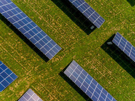 Photovoltaic farm - renewable energy from sunlight - photovoltaic panels set on a green field. Renewable energy supplying medium-sized enterprisesの写真素材