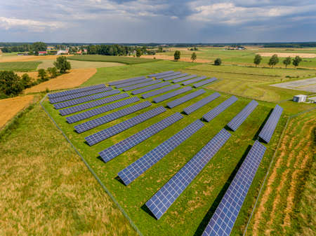 Photovoltaic farm - renewable energy from sunlight - photovoltaic panels set on a green field. Renewable energy supplying medium-sized enterprisesの写真素材