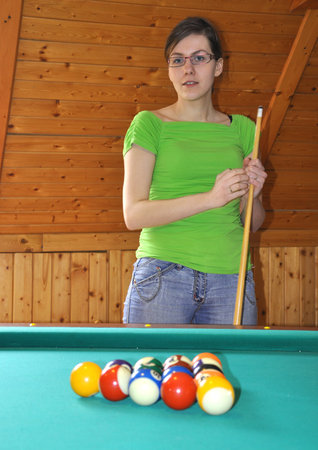 Young girl holding billard stick, ready to play a game