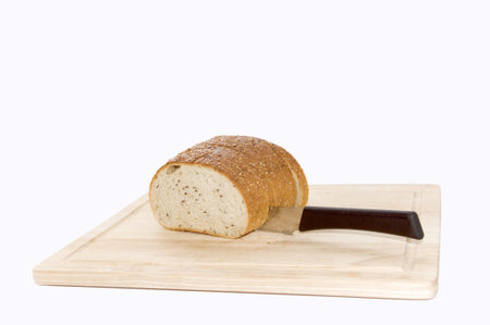 Bread cutted by knife on a wooden kitchen board, isolated on white の写真素材
