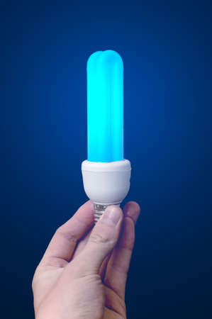 Blue lighting bulb in men handの写真素材