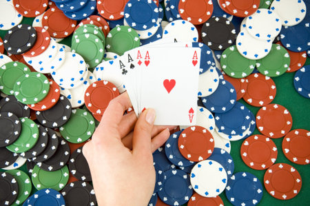 Four aces in hand, playing cards i front of casino gambling chips