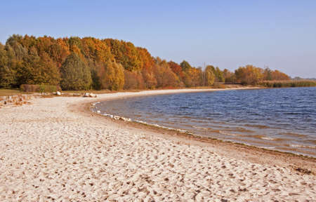 Lake with small sand beach, in colorful Autumn sceneryの写真素材
