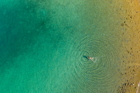Aerial view of a girl swimming in the clear sea of Brijuni National Park in Croatian Adriaticの写真素材