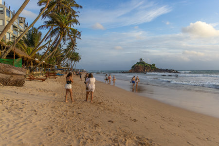 People on the sand beach in Mirissa with palms, Sri Lanka in the late afternoonのeditorial素材