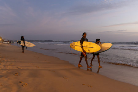 Public town beach in Weligama at sunset with surfers, Sri Lankaのeditorial素材
