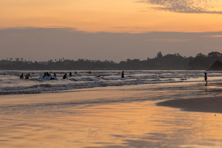 Public town beach in Weligama at sunset with surfers, Sri Lankaのeditorial素材