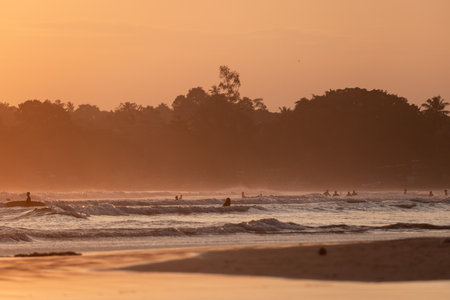 Public town beach in Weligama at sunset with surfers, Sri Lankaのeditorial素材