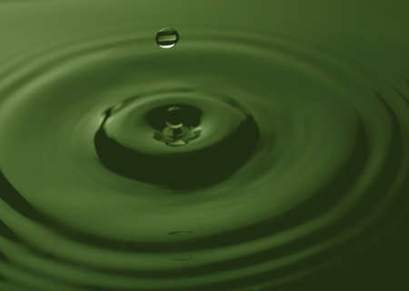 drop of water coming down into a green poolの写真素材