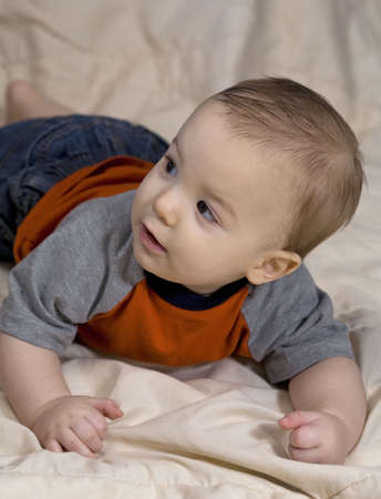 infant boy that is looking behind him at somethingの写真素材