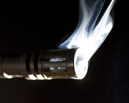 gun and its barrel that are putting out a lot of smoke