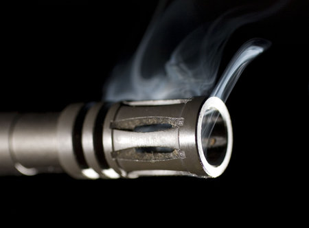 flash hider on the end of a guns barrel that is smokingの写真素材