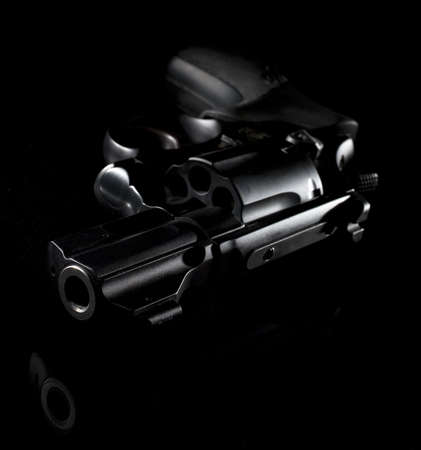 handgun that is on a reflective surface with little lightの写真素材