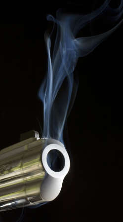 handgun that is pouring smoke just after a shotの写真素材