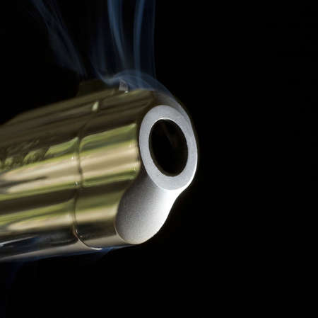 barrel of a handgun that is smoking after a shotの写真素材