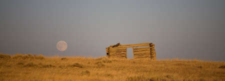 moon coming up at sunset over an abandoned cabinの写真素材